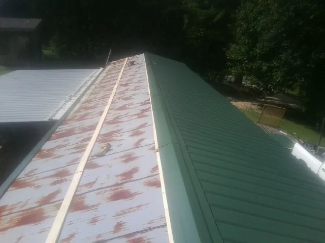 Old rusted panels beside newly installed green metal roofing — Wind Damage Roof Repair by Roofing Brothers in Swedesboro