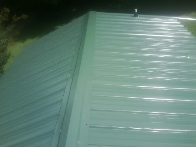 New green metal panels meeting at the ridge of a roof — Flat Roof Repair work by our crew in Swedesboro