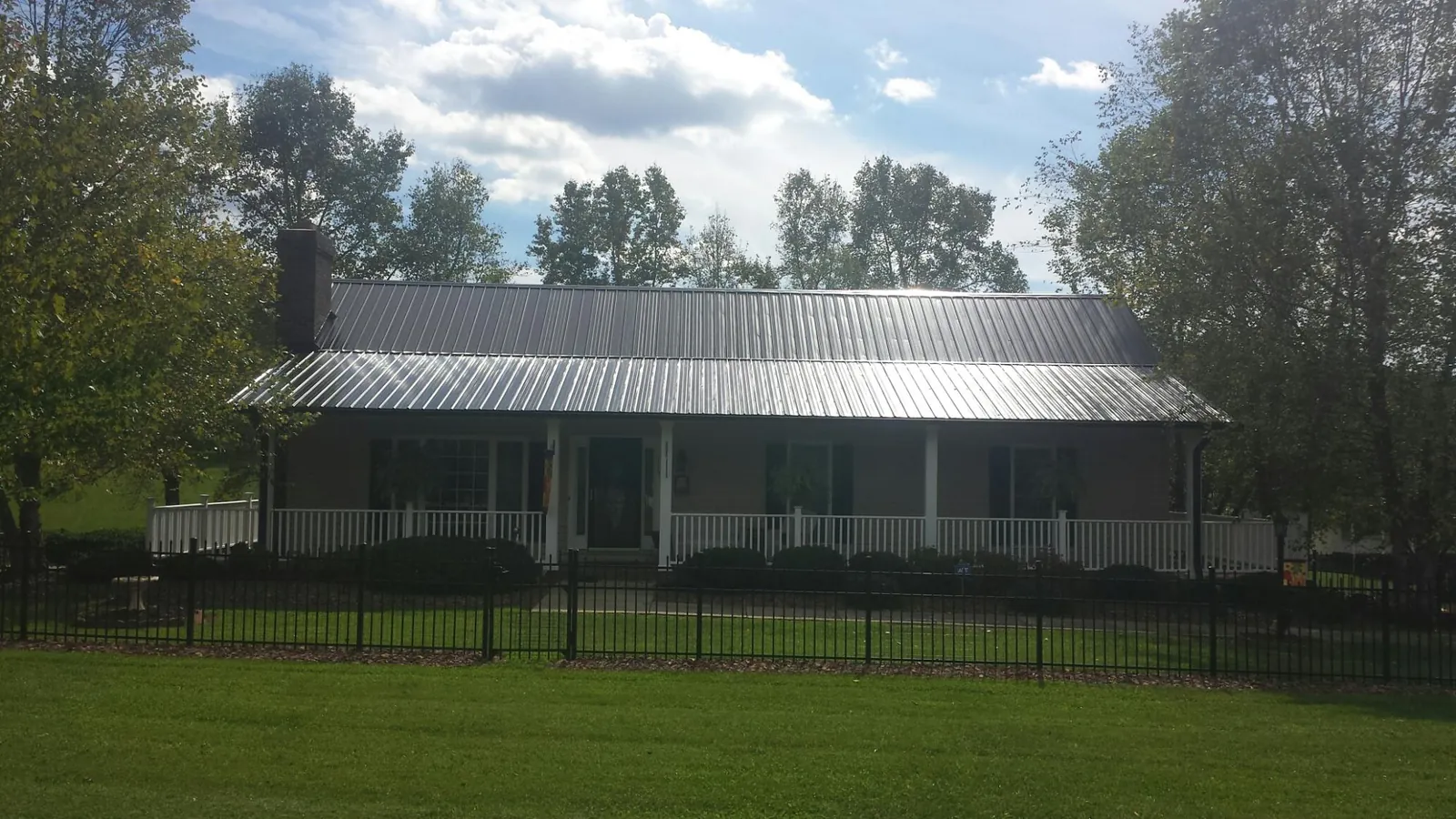 Gray metal roof on a brick ranch with a full width front porch — Gutter Guard Installation work by our crew in Swedesboro