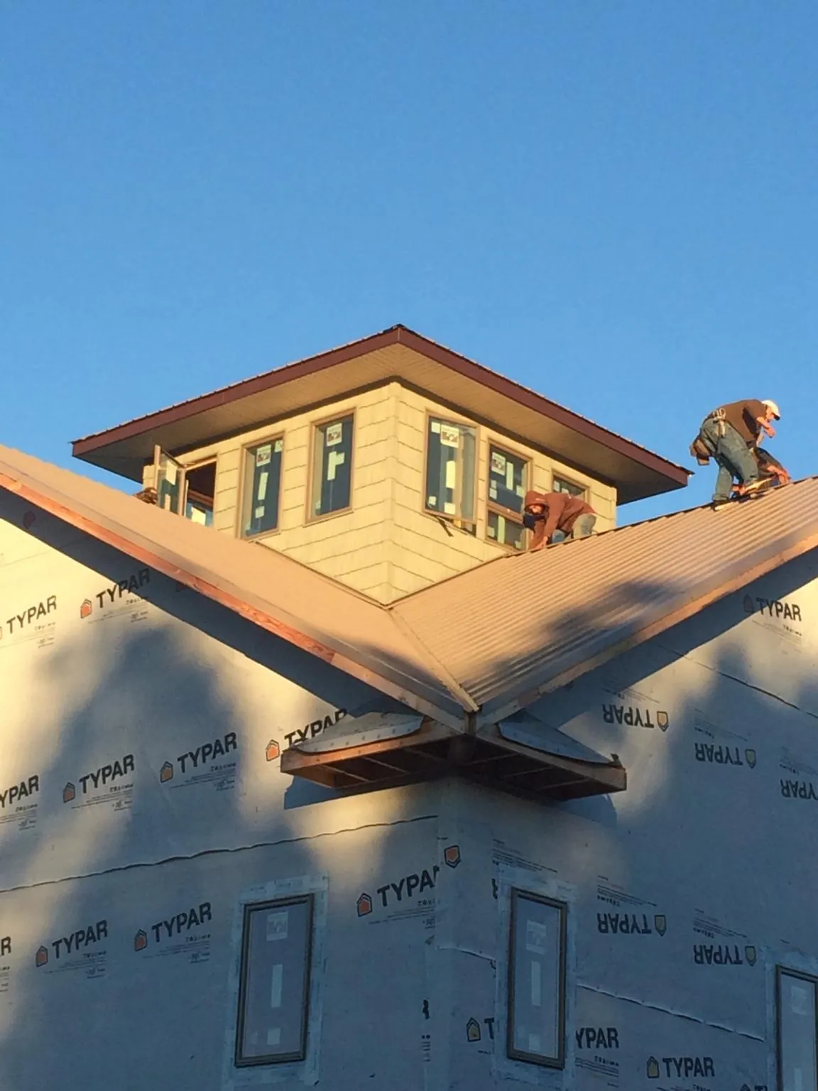 Roofers working around a rooftop cupola on a new metal roof at sunset — Roof Waterproofing in Swedesboro by Roofing Brothers